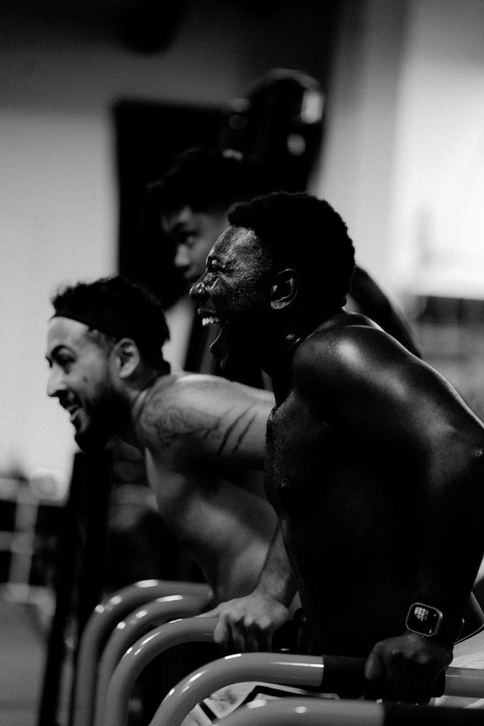 Two members side by side mid effort on the conditioning machines at Kinetic Haus