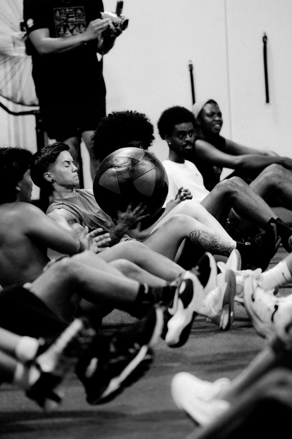 A row of members on the floor passing a medicine ball through sit-ups during a class at Kinetic Haus