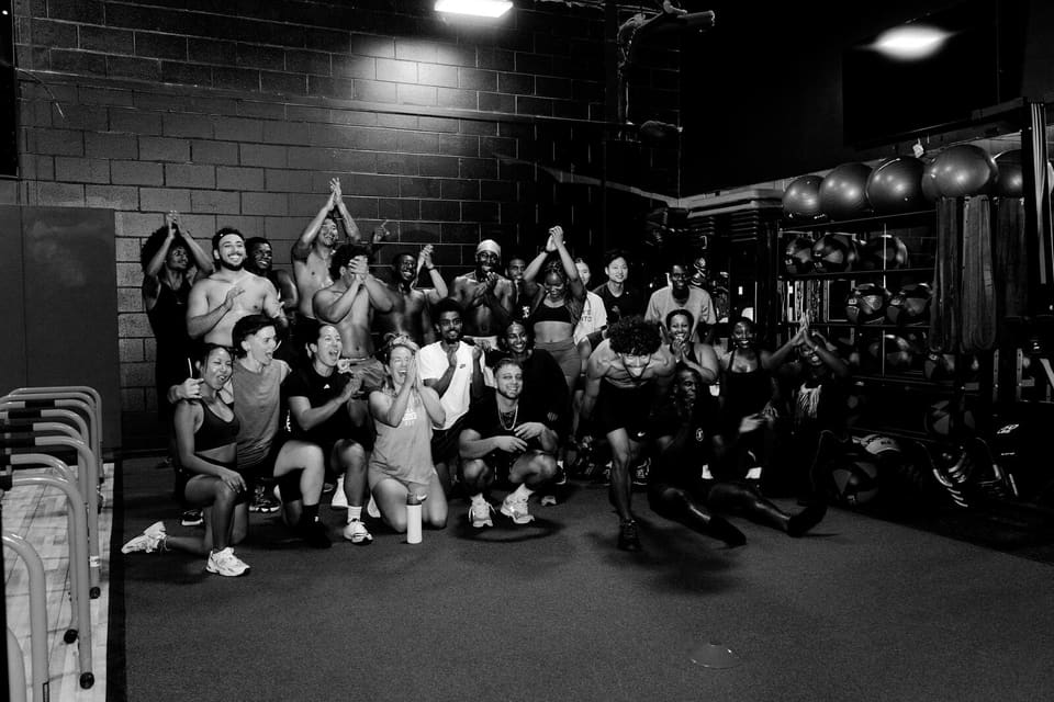 A full group class gathered on the Kinetic Haus training floor, cheering at the end of a session